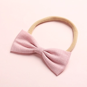 Dettaglio fascia per neonati in nylon con fiocco rosa pallido e trama del tessuto in lino