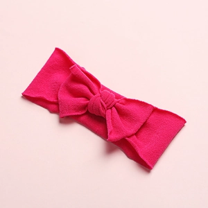 Macro detail of elastic nylon baby headband featuring a large magenta textured bow decoration