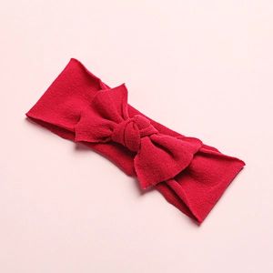 Detail shot of bright red nylon baby headband featuring soft ribbed knit texture and a large bow
