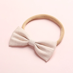 Dettaglio della fascia per neonata con fiocco in lino beige e cinturino in nylon rosa