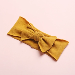 Close-up of yellow soft nylon baby headband with large knit bow and fine fabric texture