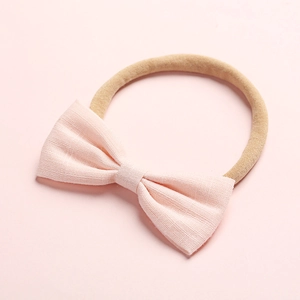 Dettaglio fascia neonata in nylon elastico con fiocco in lino rosa pallido strutturato