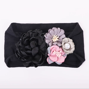 Détail du bandeau pour bébé avec des fleurs en soie colorées et des accents de perles