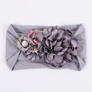 Détail d'un bandeau gris pour bébé avec fleurs en soie et petite perle synthétique