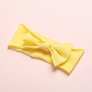 Detail of soft yellow nylon baby headband with a large bow showing breathable knit texture