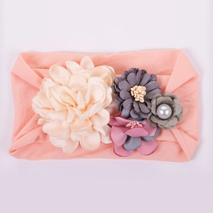 Détail d'un bandeau bébé orné de fleurs en tissu multicolores et d'une perle synthétique
