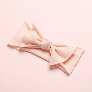 Close-up of soft light pink nylon baby headband with a three-dimensional bow design