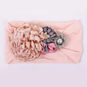 Détail de fleurs en tissu faites à la main et perle sur un bandeau pour bébé