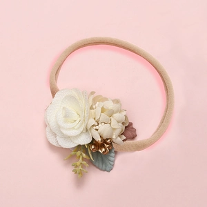 Detailed close-up of soft nylon baby headband with white fabric roses and green leaves