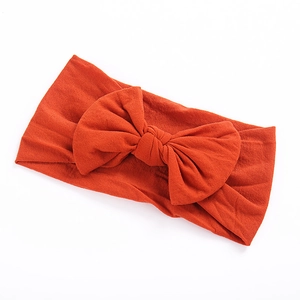 Zachte nylon elastische haarband voor baby's met een grote strik in roestoranje kleur