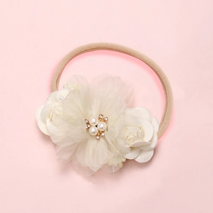 Detailed macro view of handmade cream fabric flowers with pearls on soft nylon baby headband