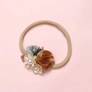 Detailed view of beige infant headband featuring satin flowers and pearl accents