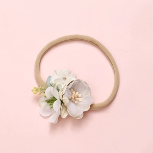Detail of soft nylon baby headband featuring purple fabric flowers and pearl accents