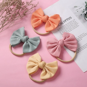 Lot de quatre bandeaux en nylon côtelé pour bébé aux couleurs pastel sur fond rose