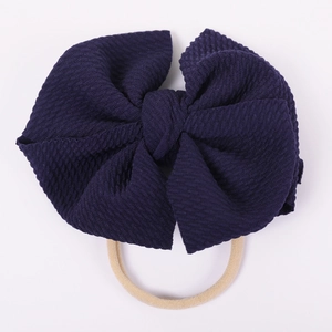 Detailed macro shot of dark blue bubble fabric bow baby headband on elastic strap