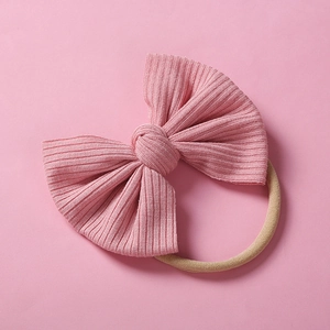 Détail du nœud rose en tissu côtelé avec bandeau en nylon beige élastique pour bébés
