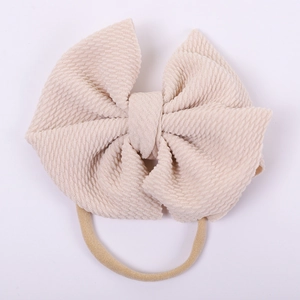 Detail of baby headband with oversized beige seersucker bow and elastic nude strap