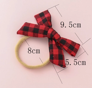 Detail of red and black buffalo plaid baby headband with size dimensions of 9.5cm bow