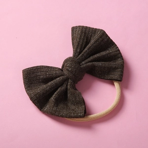 Détail d'un bandeau bébé avec nœud en tricot côtelé marron foncé et élastique nylon