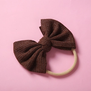Détail d'un bandeau pour bébé marron foncé avec nœud côtelé et élastique en nylon beige souple