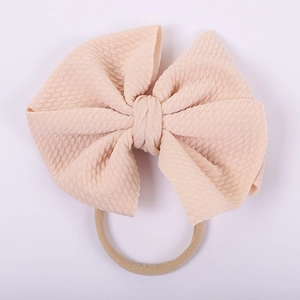 Detail of baby headband featuring soft pink honeycomb textured bow on stretchy nylon band