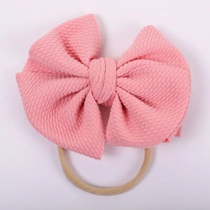 Detail of pink waffle knit texture bow on a high elasticity nylon headband for babies