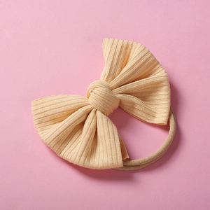 Détail du bandeau pour bébé en maille côtelée jaune pâle avec un grand nœud et élastique