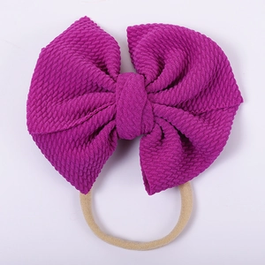 Close-up of purple waffle texture fabric bow with elastic headband for babies