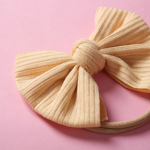 Gros plan d'un bandeau bébé en maille pêche avec nœud texturé et bande élastique en nylon
