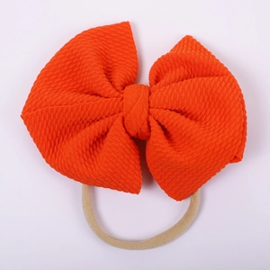 Detail of baby orange textured bubble fabric bow with seamless elastic nylon headband