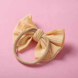 Détail d'un bandeau pour bébé avec un nœud en tricot jaune crème sur ruban en nylon