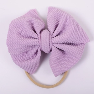 Close-up of baby headband featuring purple waffle knit bow and soft nylon elastic band