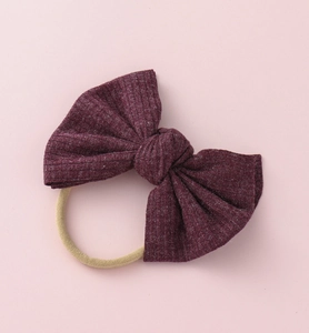 Gros plan sur un nœud bébé en tricot côtelé bordeaux sur un bandeau en nylon élastique