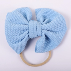 Detailed view of light blue waffle fabric bow with high elastic nylon headband for babies