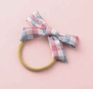 Detailed macro of pink and blue checkered fabric bow on a yellow elastic hair band