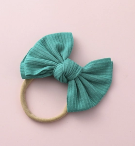 Détail du bandeau bébé avec nœud en tricot bleu sarcelle et nylon extensible