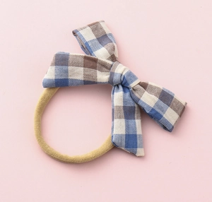 Close-up of blue and brown checkered fabric bow on a soft elastic baby hair tie