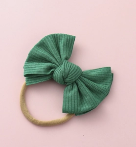 Détail de la maille côtelée d'un nœud bébé vert foncé avec bandeau en nylon