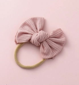 Détail du bandeau pour bébé avec nœud en tissu rose côtelé et sangle en nylon élastique