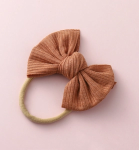 Vue détaillée du bandeau pour bébé avec nœud en maille côtelée caramel et nylon