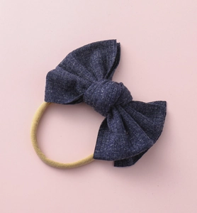 Gros plan sur un nœud en tricot bleu marine pour bébé avec un bandeau beige élastique