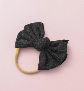 Détail du bandeau bébé avec nœud en tricot noir côtelé et bande en nylon très élastique