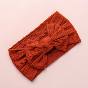 Rust red jacquard nylon baby headband with large bow detail and soft cable knit texture