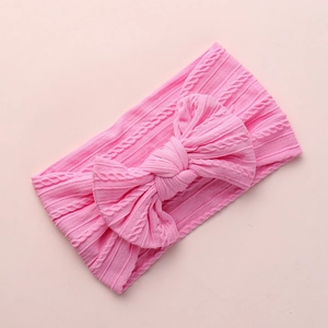Pink jacquard nylon baby headband featuring a large knitted bow with textured patterns