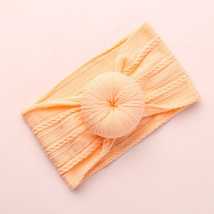 Soft apricot jacquard knit baby headband featuring a cute large donut knot design