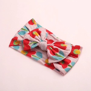 Détail d'un bandeau rose à fleurs pour bébés avec un nœud en maille élastique douce