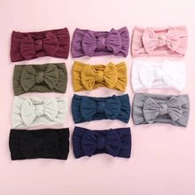 Detail view of 11 multi-color soft nylon infant headbands with large ribbed knit bows