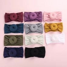Detailed view of 11 multi-colored soft nylon baby headbands with donut knot design
