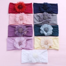 Flat lay of nine colorful soft nylon baby headbands with large floral ornaments