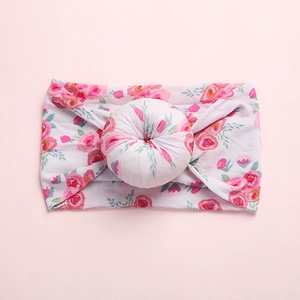 Close-up of soft floral nylon baby headband with 3D donut knot on pink background